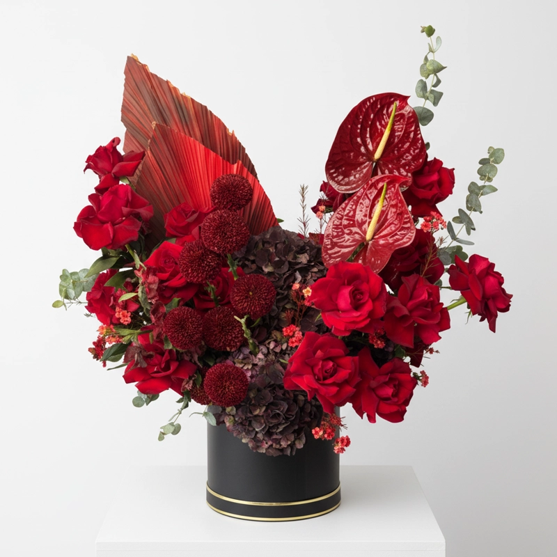 Exotic red floral arrangement featuring Anthurium, red roses, and dried palm in a black box, a luxury statement piece delivered in the UAE.